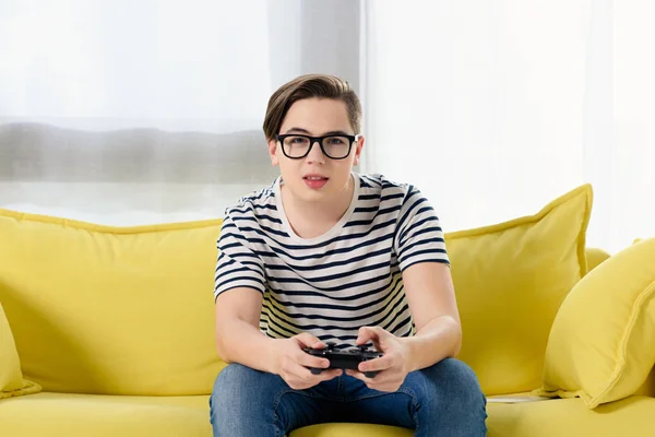 Adolescent garçon jouer jeu vidéo sur canapé à la maison — Photo de stock