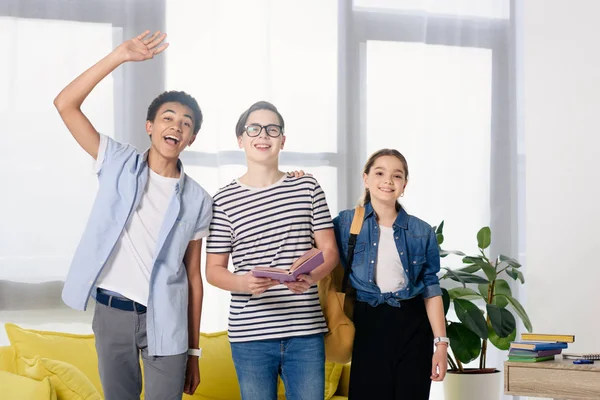 Lächelnde multikulturelle Teenager begrüßen jemanden zu Hause — Stockfoto