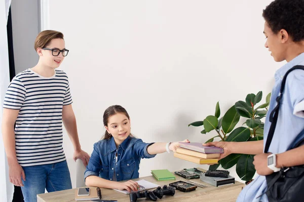 African american teenager passing books to friend at home — Stock Photo