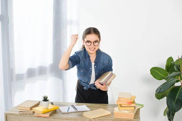 Angry preteen child holding books and showing fist at home — Stock Photo
