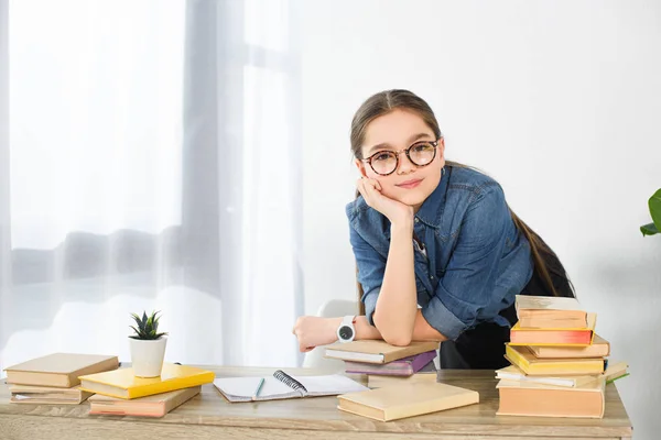 Entzückende Frühchen Kind ruht Kinn auf der Hand am Tisch mit Büchern zu Hause — Stockfoto