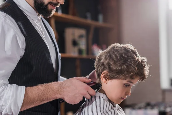 Cropped shot of barber cutting hair of little kid with Hair Clipper — Stock Photo