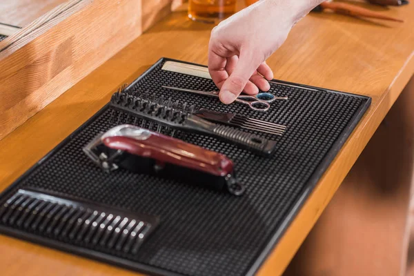 Cropped shot of barber taking scissors from rubber mat on workplace — Stock Photo