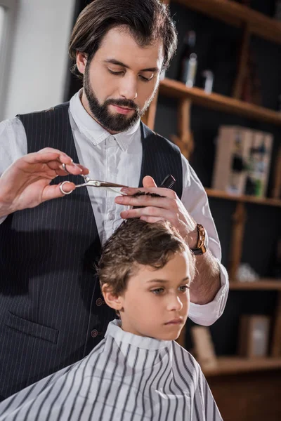 Curly little kid getting haircut at kids barbershop — Stock Photo