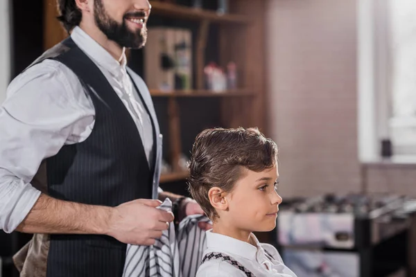 Side view of adorable little kid sitting on chair at kids barbershop — Stock Photo