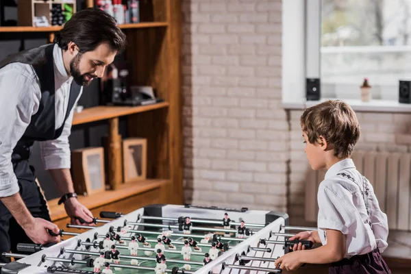 Bonito barbudo pai e pequeno filho jogar futebol de mesa — Fotografia de Stock