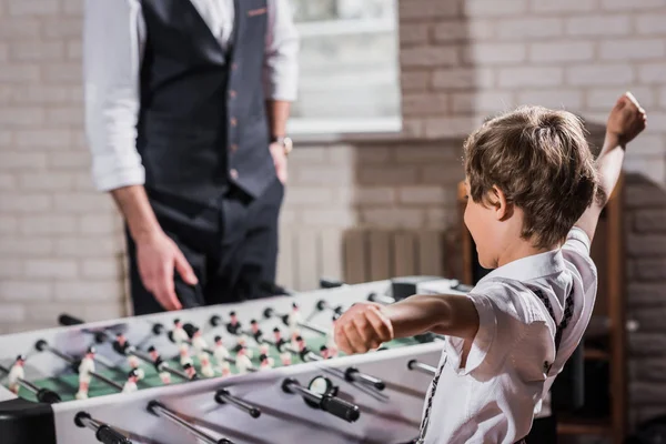 Niño pequeño con estilo jugando futbolín con padre - foto de stock