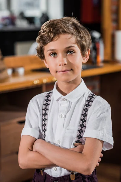 Adorable little kid with crossed arms at barbershop — Stock Photo