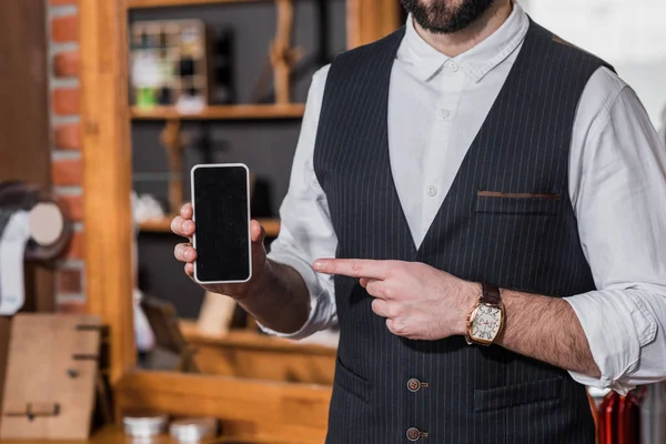 Schnappschuss von Friseur in Weste zeigt auf Smartphone — Stockfoto