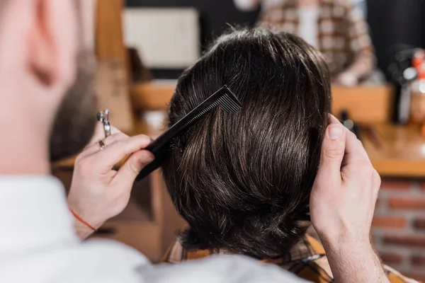 Tiro cortado de barbeiro pentear o cabelo do cliente na barbearia — Fotografia de Stock