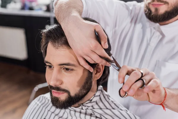 Sonriente barbudo hombre consiguiendo corte de pelo en barbería - foto de stock