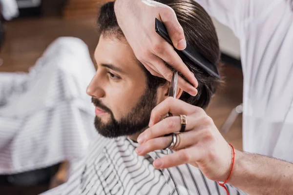 Cortado tiro de peluquero corte de pelo del cliente con tijeras - foto de stock