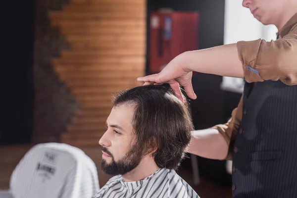 Tiro recortado de peluquero peinando el pelo del cliente en la barbería - foto de stock