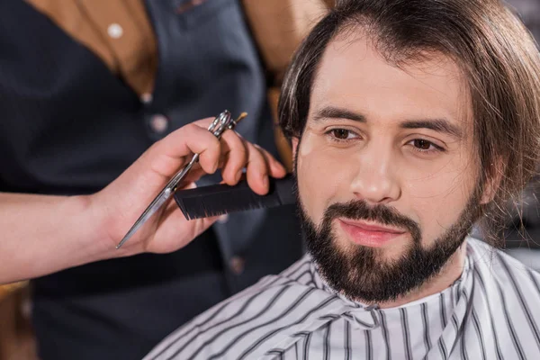 Plan rapproché d'un jeune homme souriant se faisant couper les cheveux au salon de coiffure — Photo de stock
