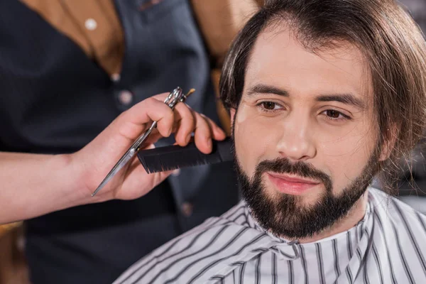 Primer plano de sonriente joven recibiendo corte de pelo en la barbería - foto de stock