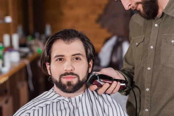 Barbier rasage heureux beau client avec tondeuse à cheveux — Photo de stock