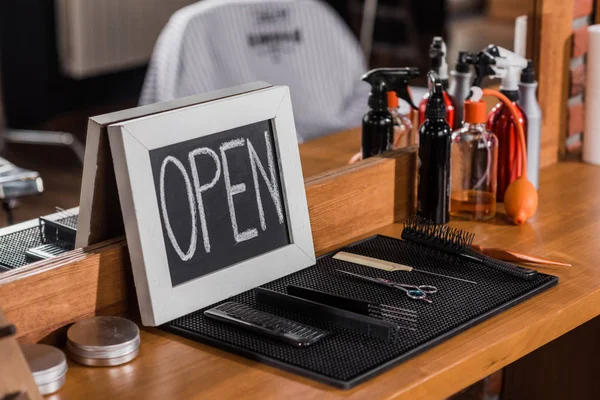 Close-up shot of blackboard with open sign leaning on mirror at barbershop — Stock Photo