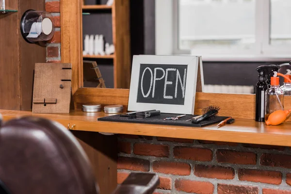 Blackboard with open sign leaning on mirror at barbershop — Stock Photo