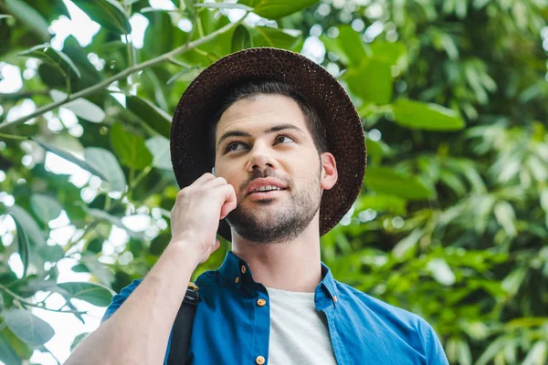 Vista dal basso di bel giovane uomo che parla per telefono nella foresta — Foto stock