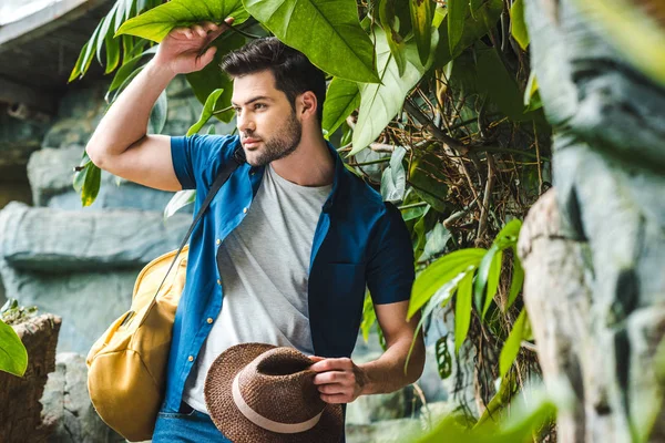 Schöner junger Mann in stylischer Kleidung mit Strohhut im Regenwald — Stockfoto