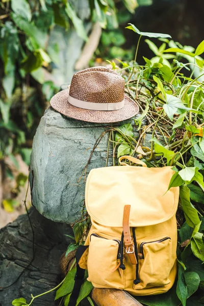 Zaino giallo vintage e cappello di paglia su roccia nella giungla — Foto stock