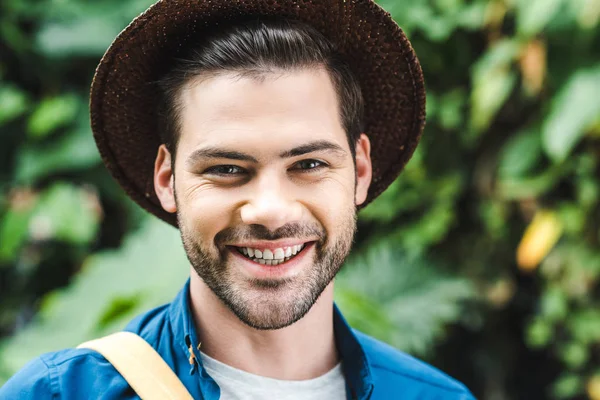 Retrato de cerca de un joven sonriente con sombrero de paja en la naturaleza - foto de stock