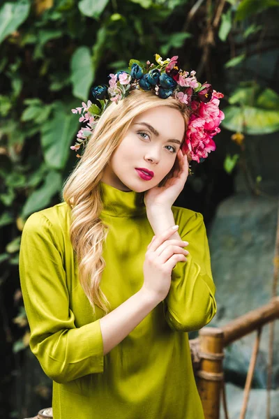Bella giovane donna con corona floreale guardando la fotocamera — Foto stock
