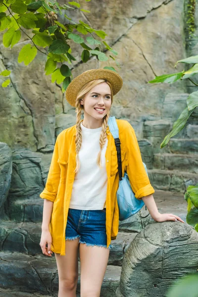 Beautiful young woman in straw hat on stone stairs in park — Stock Photo