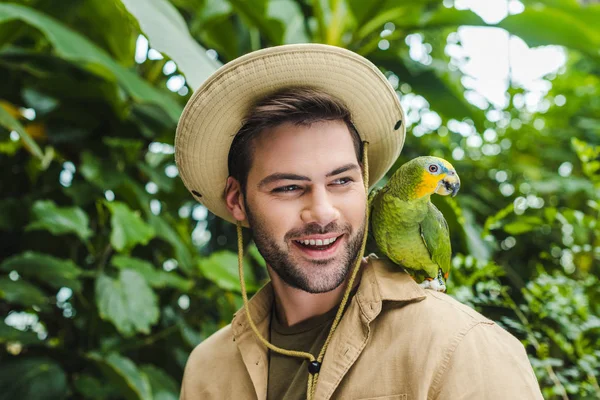 Красивий молодий чоловік з папугою на плечі — стокове фото