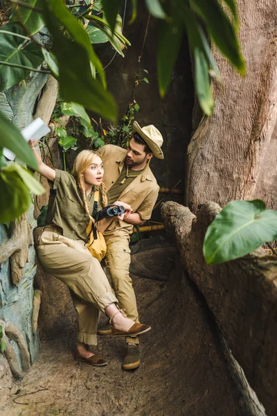 Красивый мужчина поддерживает свою девушку, пока они путешествуют по джунглям — стоковое фото