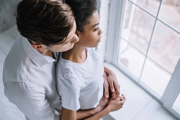 Jeune couple embrasser et regarder dans la fenêtre — Photo de stock