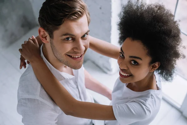 Africano americano chica abrazando novio por luz pared - foto de stock