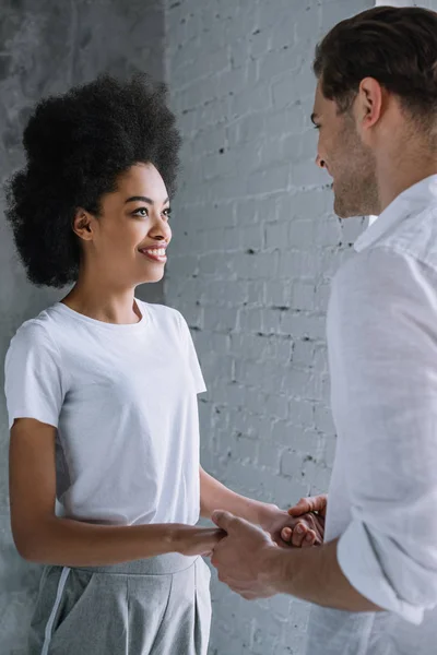 Vielrassiges Paar hält Händchen an Lichtwand — Stockfoto