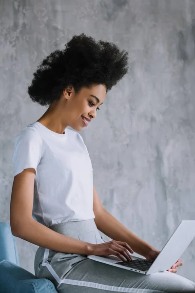 African american girl using laptop while sitting on sofa — Stock Photo