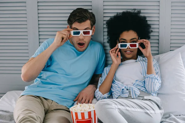 Petit ami multiracial et petite amie dans des lunettes stéréoscopiques regarder un film à la maison avec du pop-corn — Photo de stock