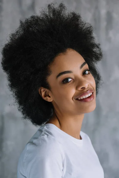 Sonriente chica afroamericana bonita sobre fondo gris de la pared - foto de stock
