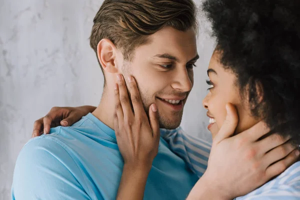 Joven hombre y mujer abrazando por la pared gris - foto de stock