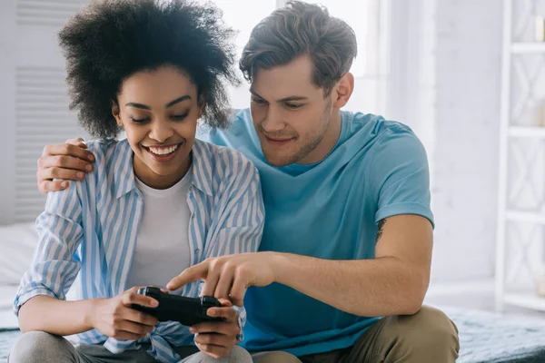 Hombre explicando a la mujer afroamericana cómo usar el joystick - foto de stock