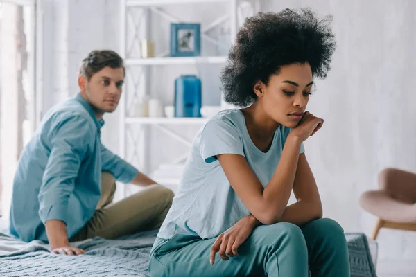 Aufgebracht afrikanisch amerikanisch mädchen sitzen auf bett von ihrem freund — Stockfoto