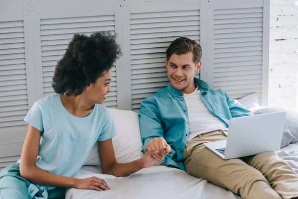 Afro-americana chica de la mano de su novio en la cama con el ordenador portátil - foto de stock