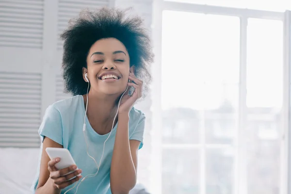 Sonriente chica afroamericana disfrutando de la música en los auriculares — Stock Photo
