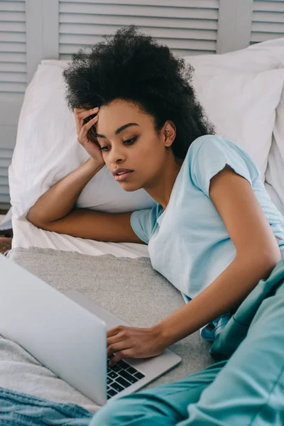 African american woman using laptop in bed — Stock Photo