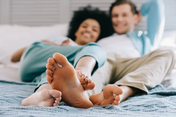 Close-up view of feet of multiracial couple staying in bed — Stock Photo