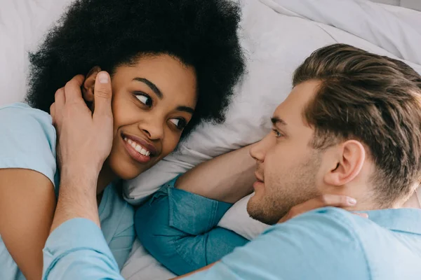 Jolie couple multiracial étreignant et couché sur le lit — Photo de stock