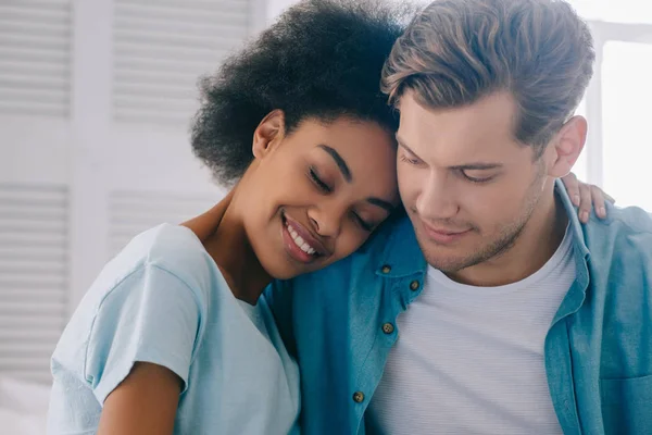 Africano americano chica abrazando novio mientras sentado en cama - foto de stock