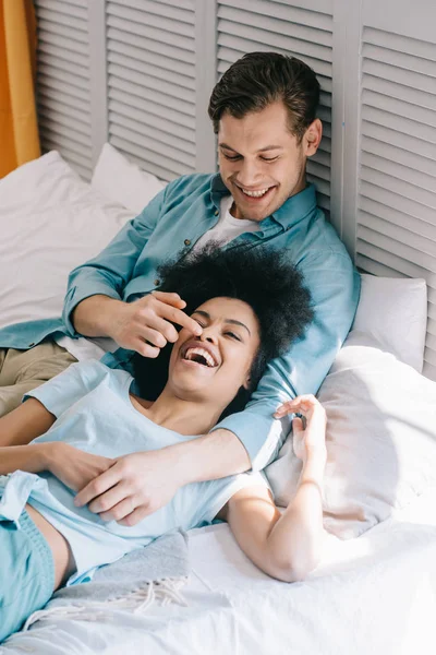 Amar casal multirracial se divertindo na cama em casa — Fotografia de Stock