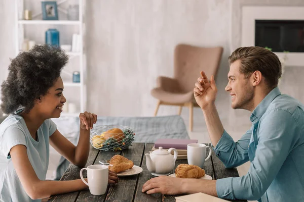 Felice coppia multirazziale godendo la colazione a casa — Foto stock