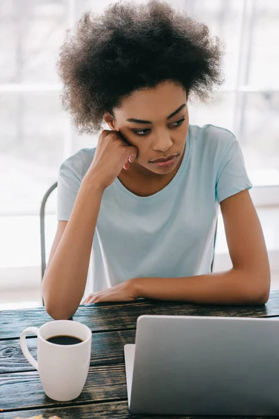 Donna afro-americana sconvolta seduta dal computer portatile a casa — Foto stock