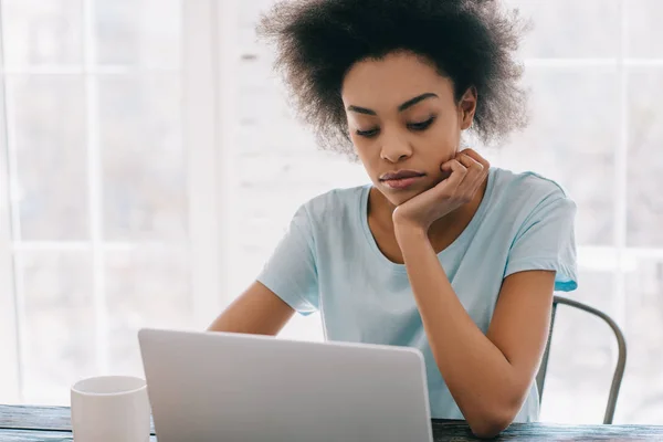 Pensativo mujer afroamericana que trabaja en el ordenador portátil en casa - foto de stock