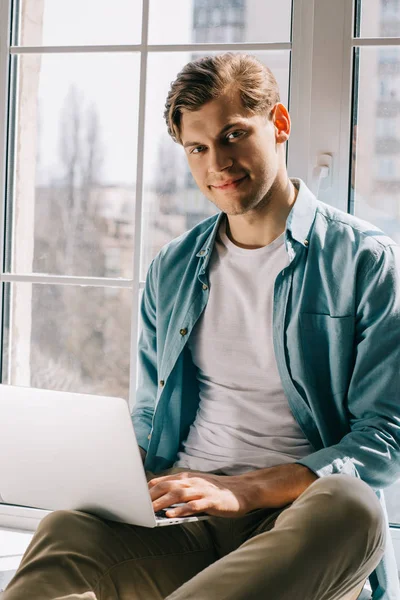 Man using laptop while sitting by window — Stock Photo